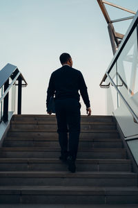 Rear view of man on staircase against sky