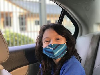 Portrait of beautiful girl in car with face mask on 