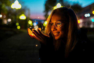 Portrait of young woman using smart phone at night