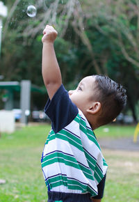 Close-up of boy playing with bubbles in park