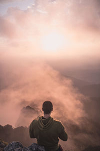 Rear view of man standing on mountain against sky