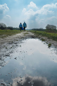 Rear view of people walking on beach against sky