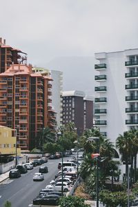 Cars on street in city against sky