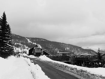 Snow covered buildings by mountain against sky