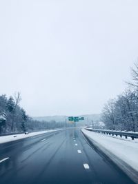 Cars on road against clear sky during winter