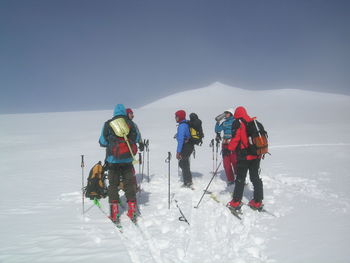 People standing on snowcapped mountain against clear sky