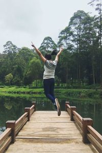 Full length of man jumping over lake against sky