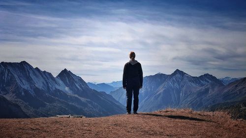 Rear view of woman standing on mountain against sky