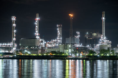 Illuminated factory against sky at night