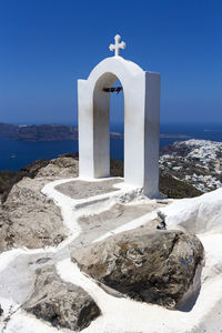 Built structure by sea against clear blue sky