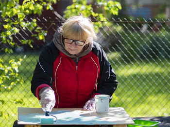 Portrait of woman wearing mask against fence