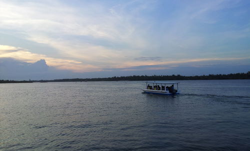 Boat sailing in sea against sky during sunset