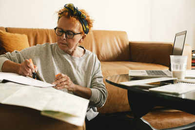 Senior woman planning trip while sitting in living room at home