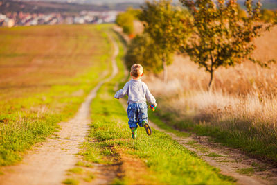 Rear view of girl walking on field