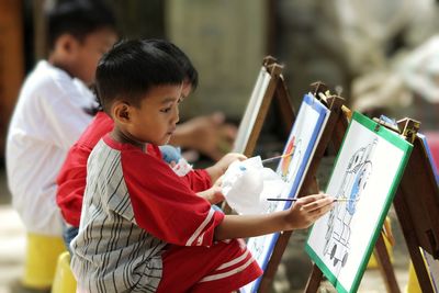 The boy is coloring the picture.