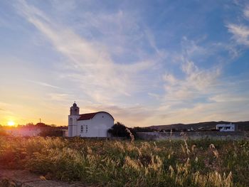 House on field against sky during sunset