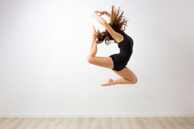 Woman with arms raised against white wall