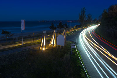 Light trails on road against sky at night