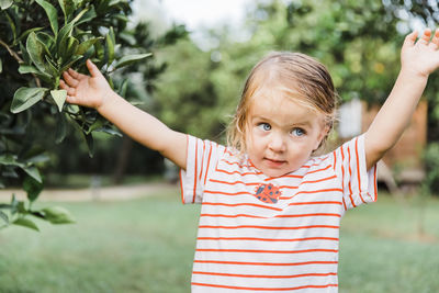 Cute girl with arms raised standing outdoors