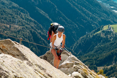 Full length of woman climbing rocks in a mountain at heini-holzer-klettersteig, meran 2000