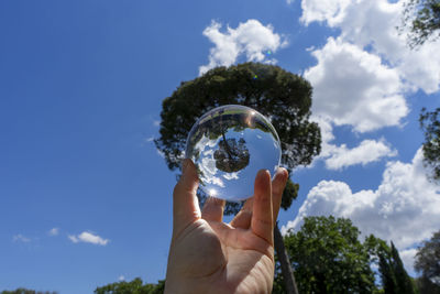 Low angle view of person holding umbrella against blue sky