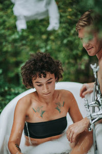 Portrait of shirtless man with woman sitting outdoors