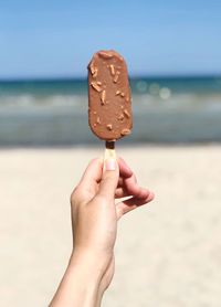 Close-up of hand holding ice cream cone on beach