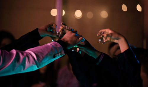 Close-up of hands toasting shot glasses in night club