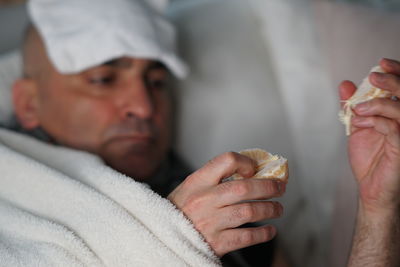 Close-up of man having orange while lying on sofa