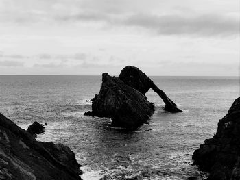 Rock formation in sea against sky