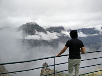 Rear view of woman standing on mountain against sky