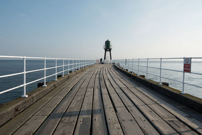 Rear view of pier on sea against sky
