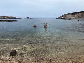 People swimming in sea against sky