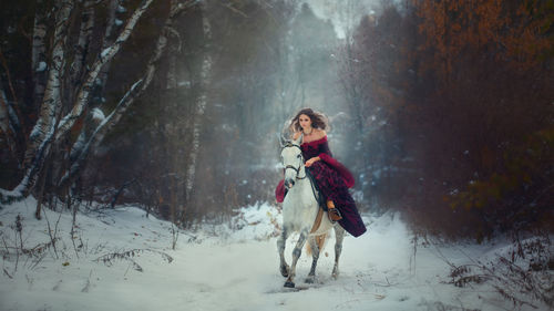 Full length of woman with dog in snow at forest