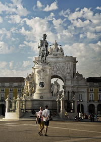 Statue in city against cloudy sky