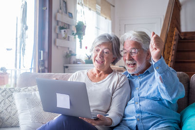 Cheerful senior couple talking on video call at home