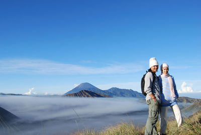 Couple on mountain against blue sky