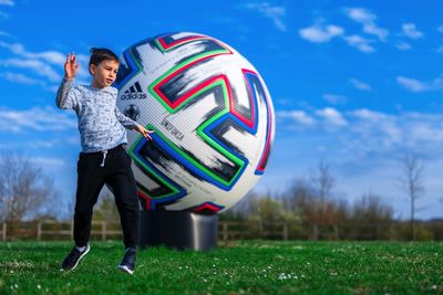 Boy standing on field against sky