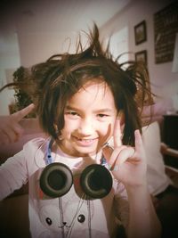 Portrait of smiling girl with headphones gesturing at home