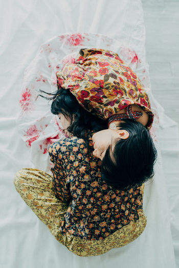 HIGH ANGLE VIEW OF WOMAN WITH DAUGHTER ON BED