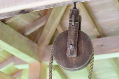 Low angle view of metal hanging on rope against wall