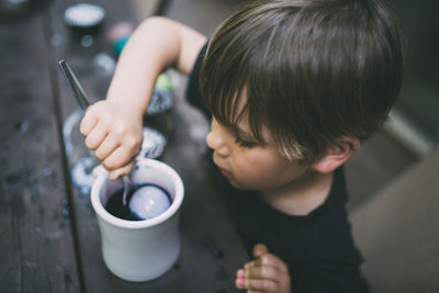 High angle view of boy coloring easter egg