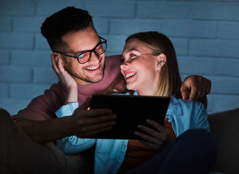 Man and woman using smart phone while sitting outdoors