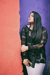 Young woman standing against wall