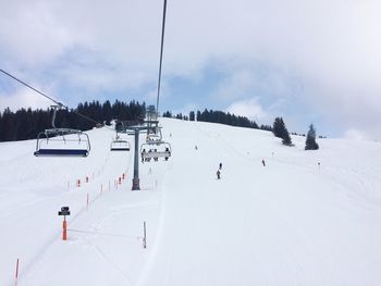 Ski lifts over snow covered landscape against sky