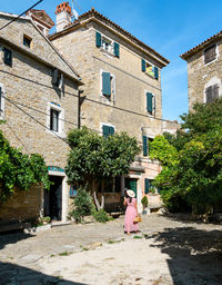 Young woman in pink dress walking in square of picturesque old town.