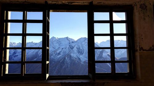 Scenic view of snow covered mountains seen through window