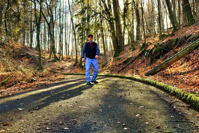 Rear view of man walking on road in forest