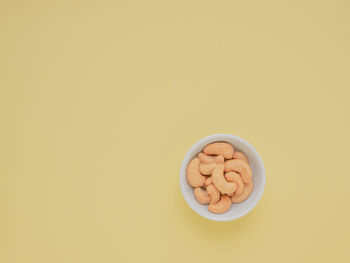 High angle view of cashew in bowl on yellow background