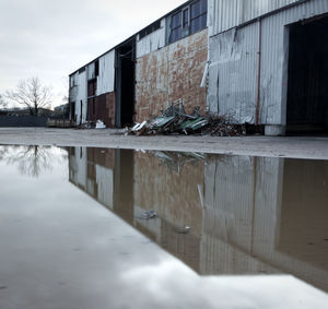 Abandoned building by canal against sky